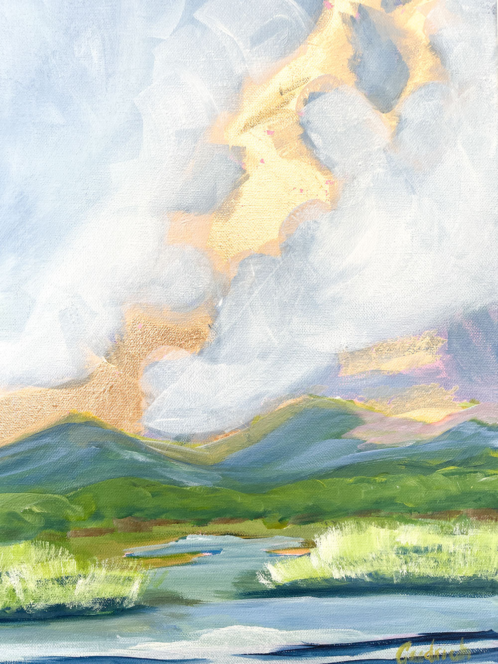 a detail of the 24" x 18" gold leaf landscape painting by Sally J Goodrich. A mix of gold leaf and acrylic paint create gorgeous landscape of the blue ridge mountains. A dramatic moody blue sky with gold rising sun highlights over the mountains, behind native trees and shrubs banking a babbling brook through a field of native grasses.