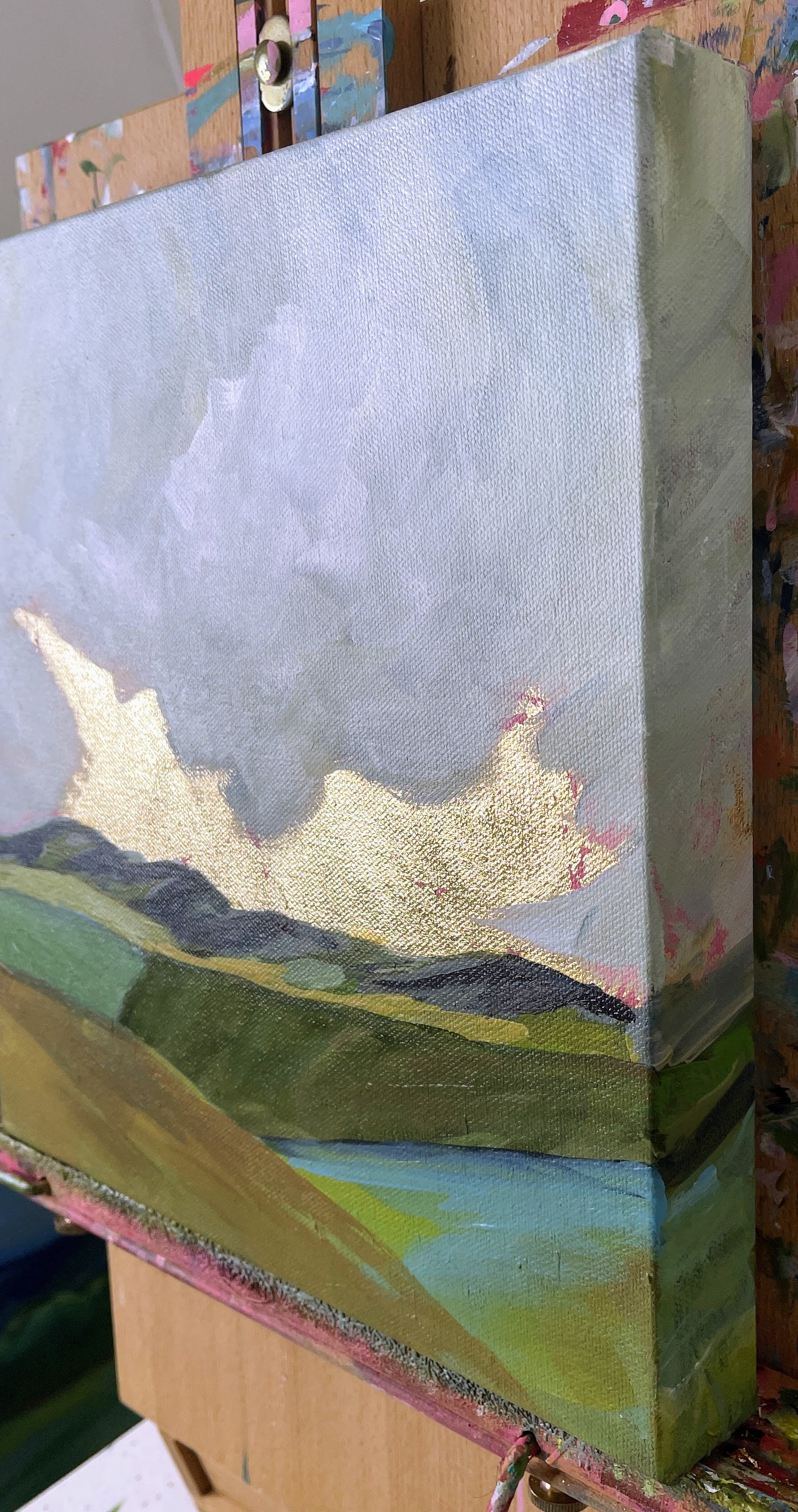 Artistic depiction of a landscape with mountains and a sky, possibly made from paper or fabric, on a textured surface.