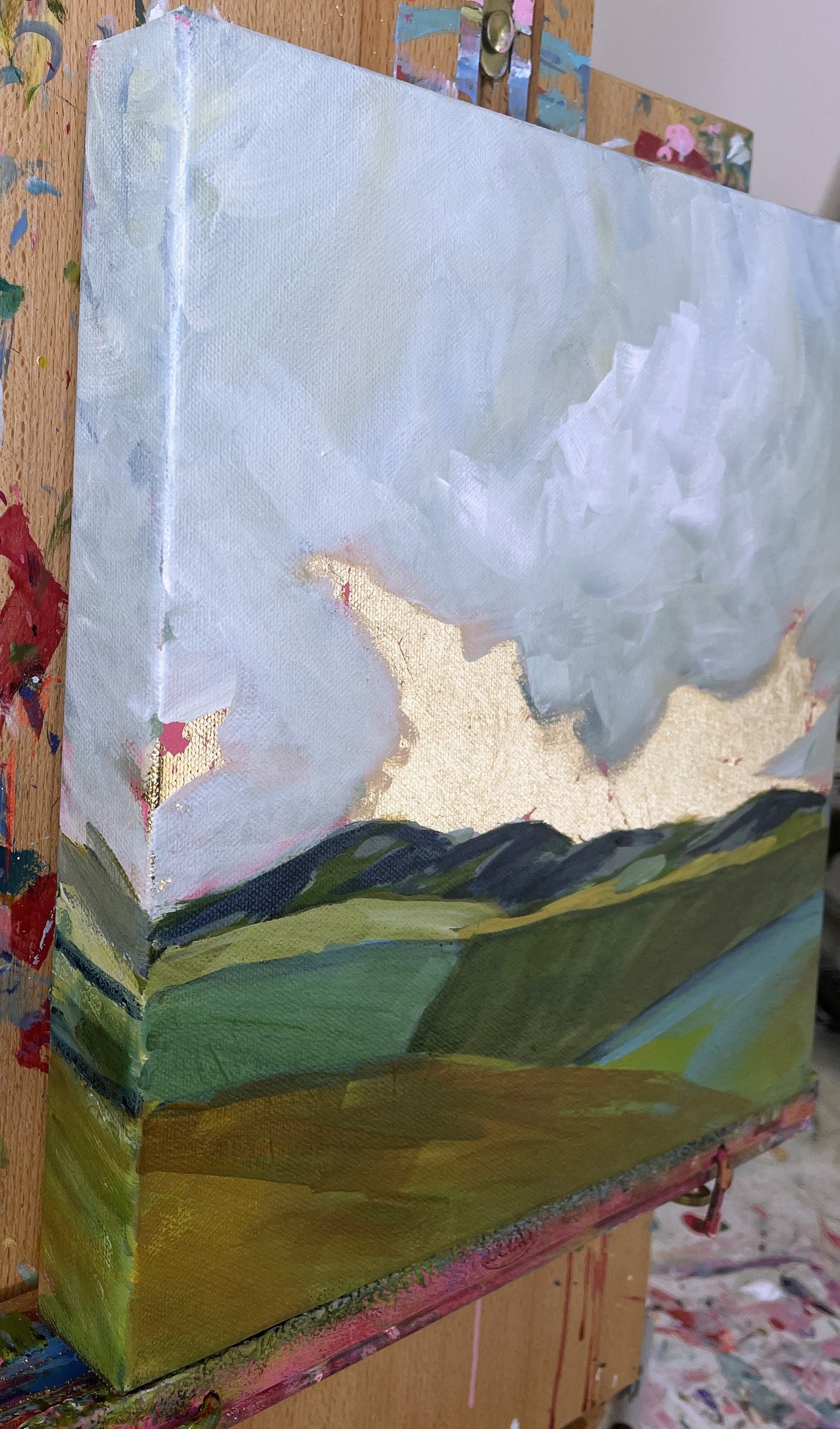 Artistic depiction of a mountain landscape with gold accents on a textured surface.