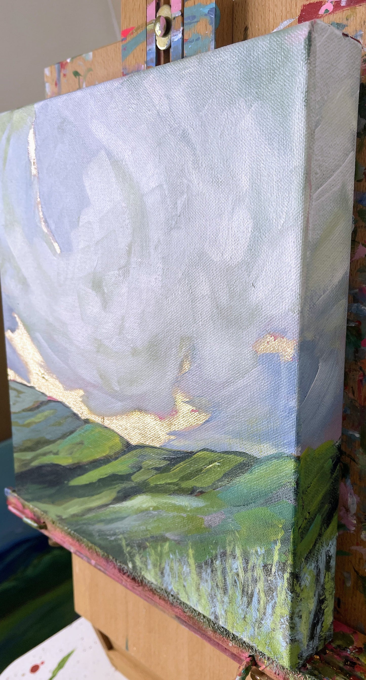 Small landscape painting on a wooden panel with a focus on the sky and fields.